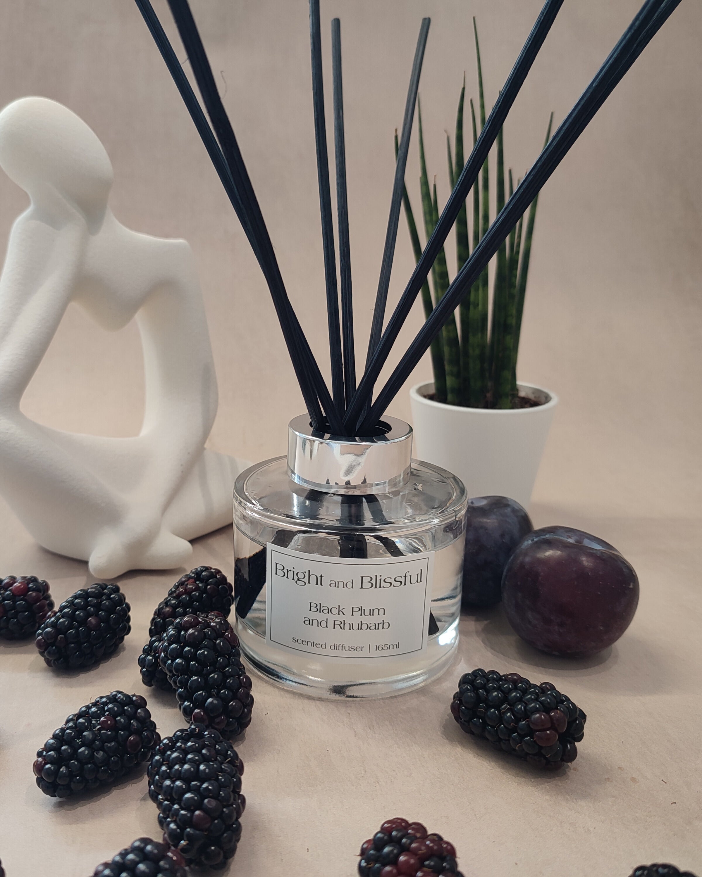 Aromatherapy diffuser with blackberries and a decorative figure on a neutral background