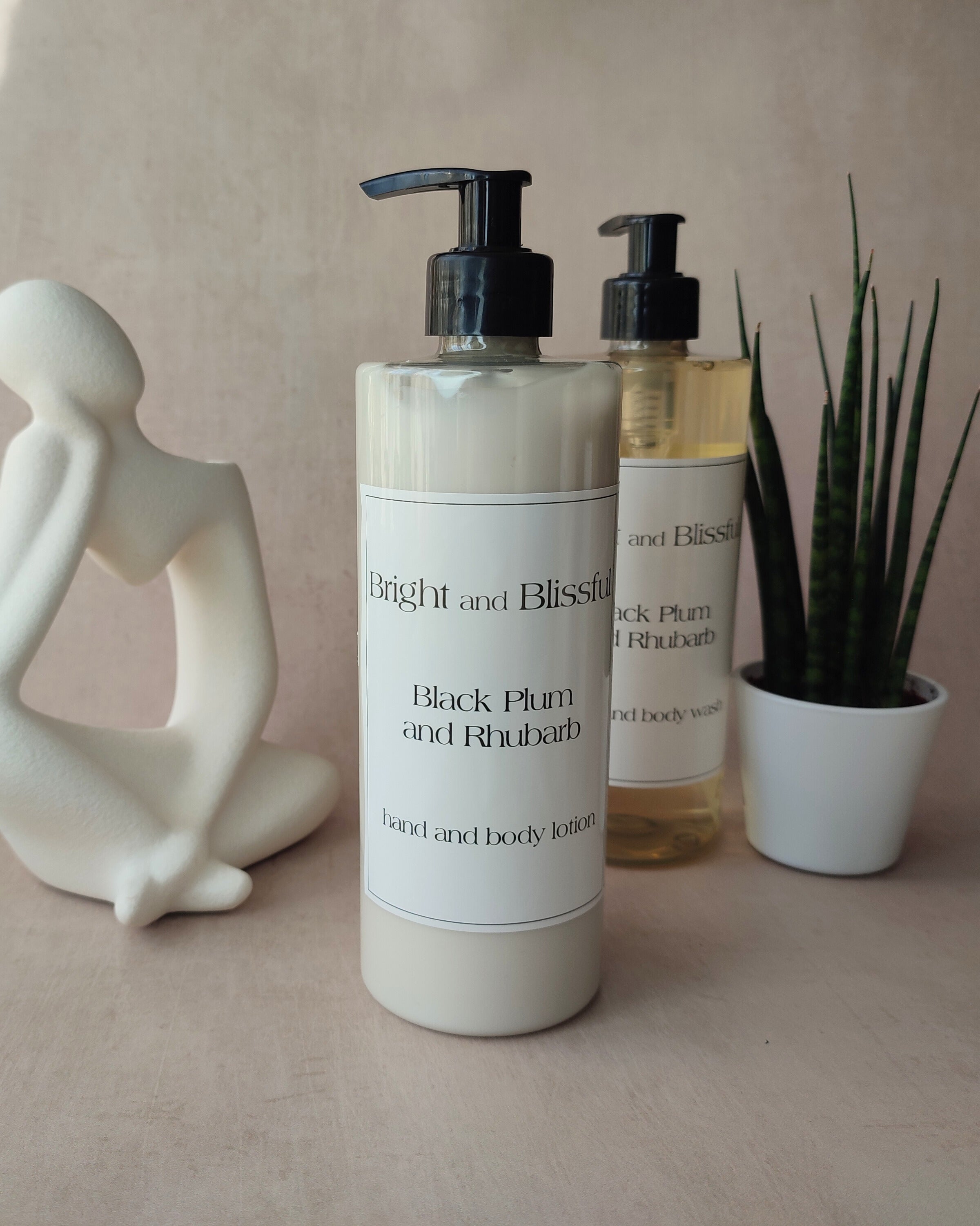 Two bottles of 'Bright and Blissful' body lotion on a neutral surface with decorative elements.