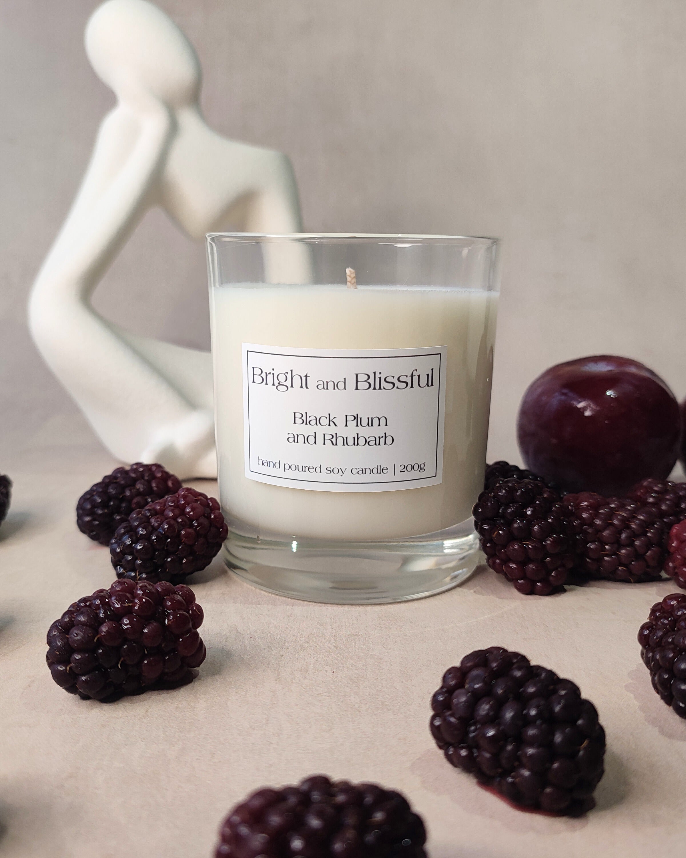 candle surrounded with a white statue,blackcurrants and a plum