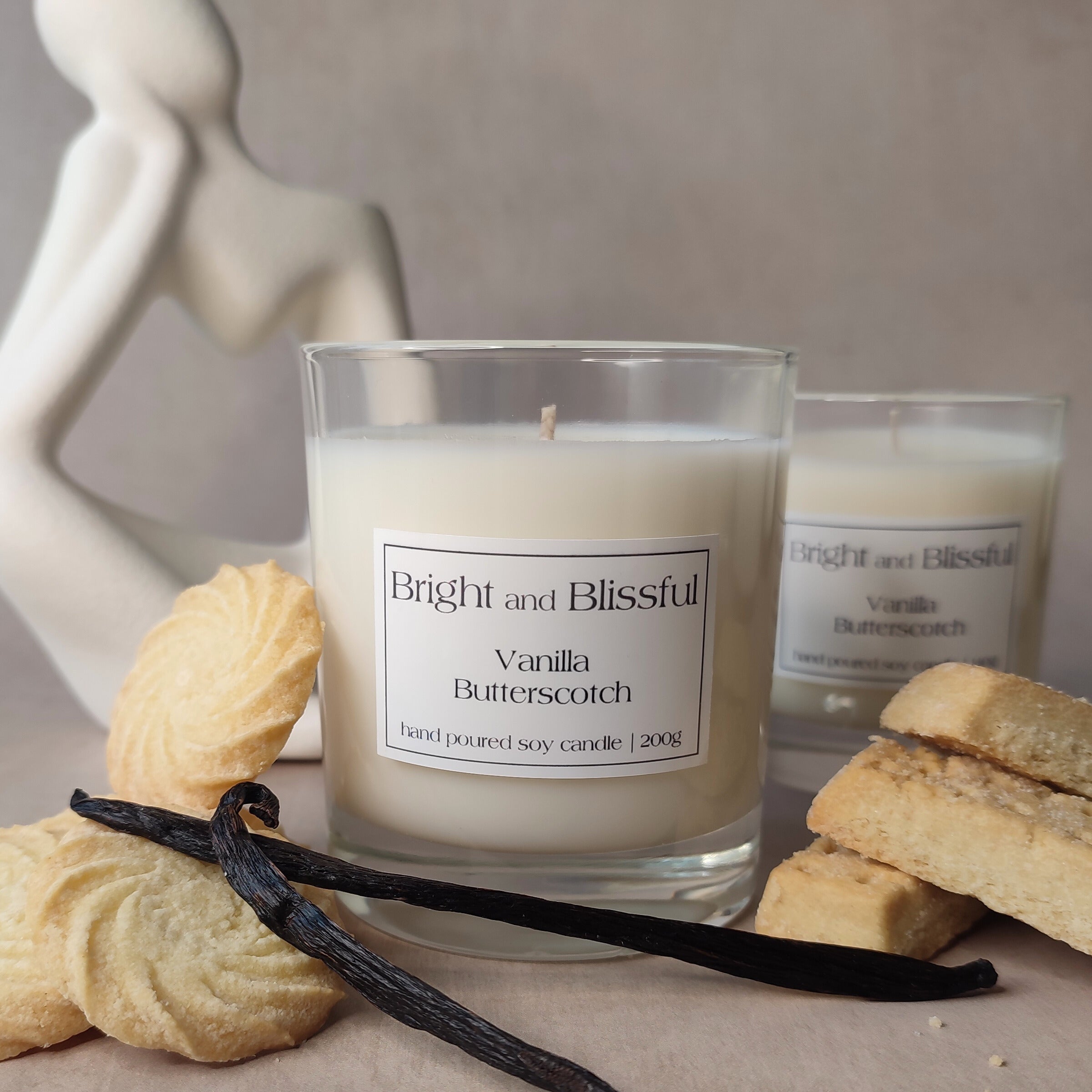 Vanilla butterscotch candle with packaging and cookies on a neutral background