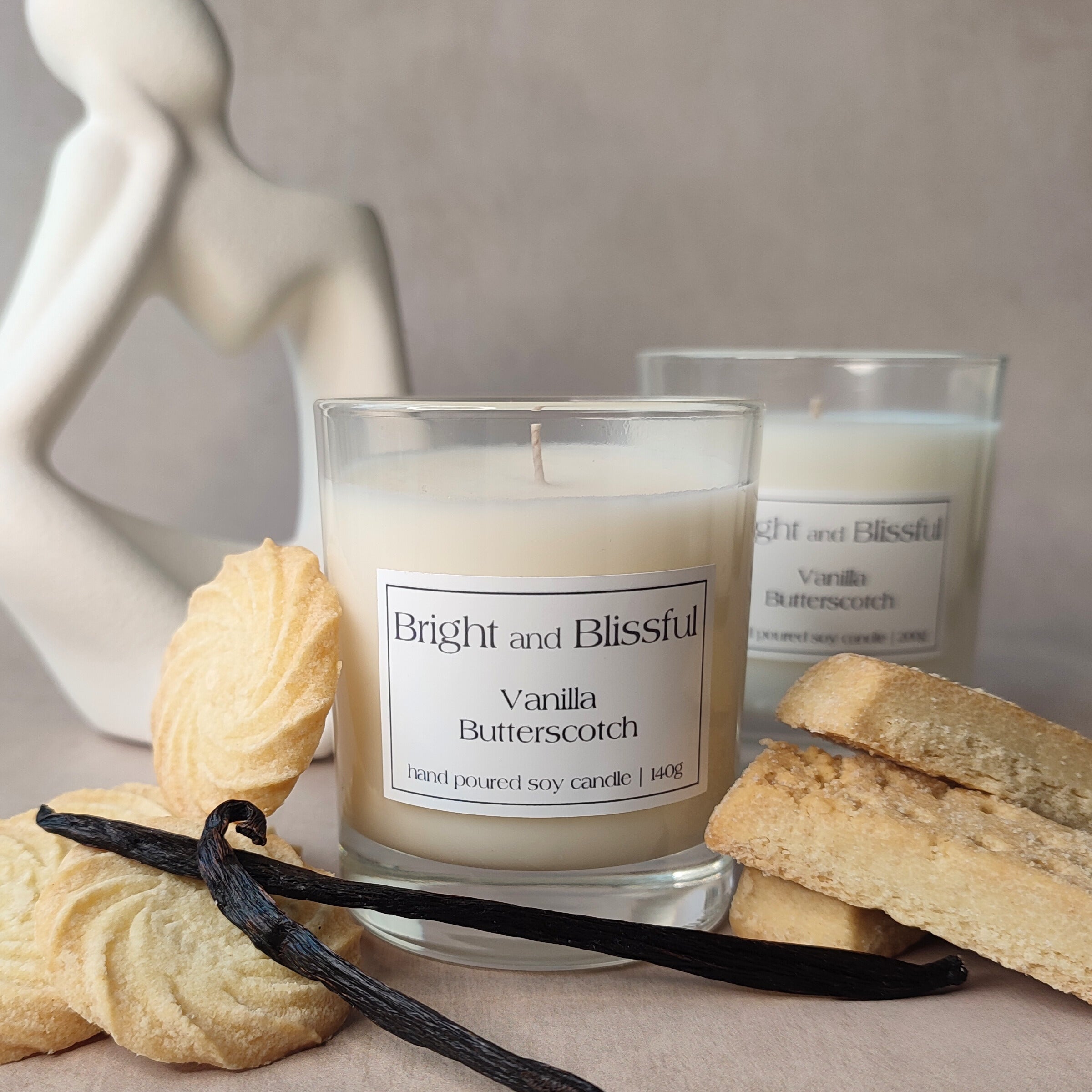 Vanilla butterscotch candle with vanilla beans and cookies on a neutral background