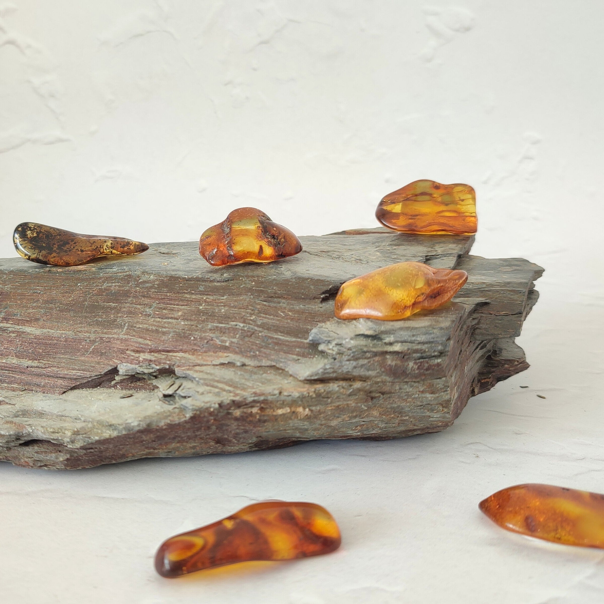 Amber stones on a piece of slated rock with a white background
