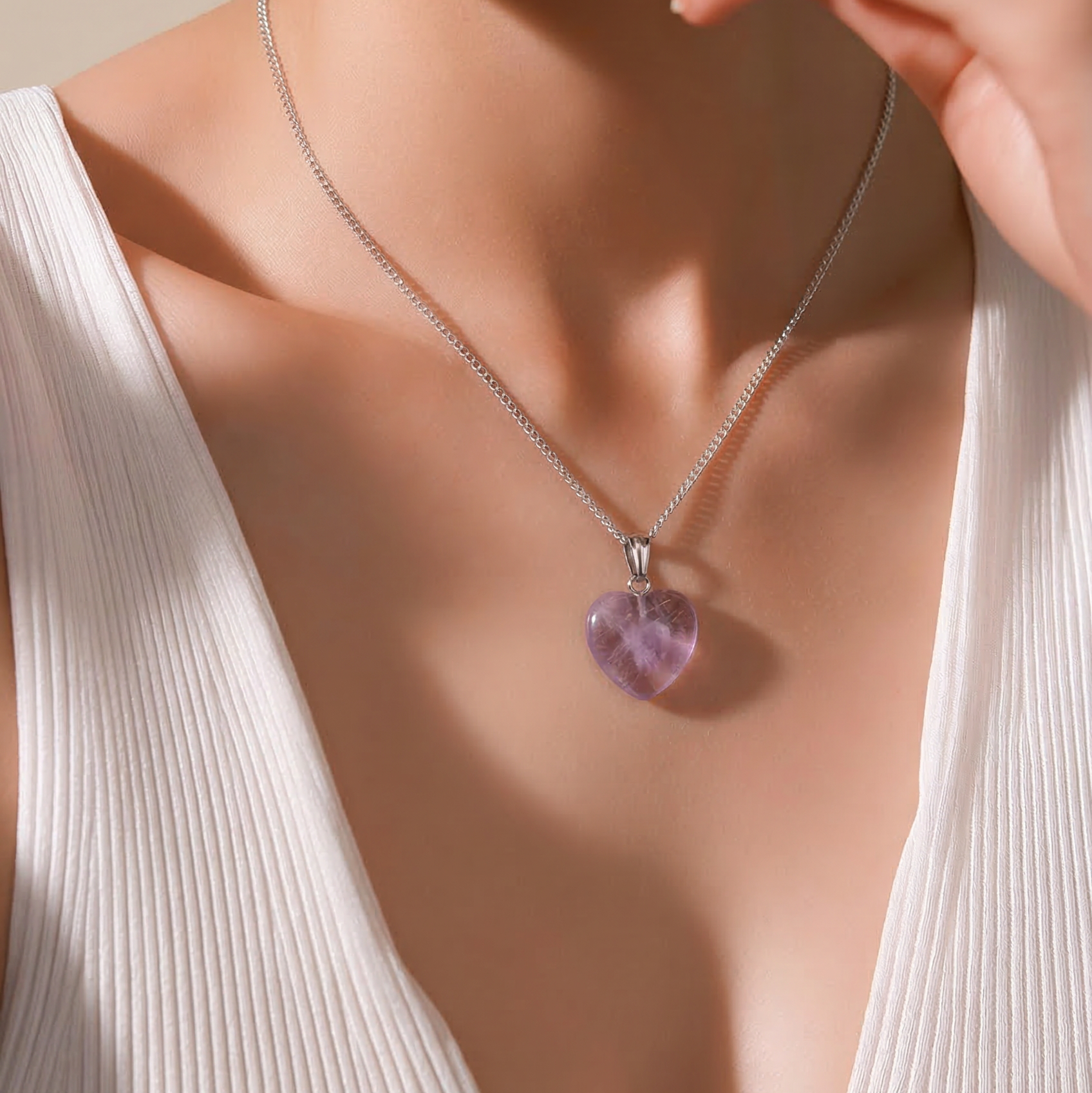 Necklace with a purple amethyst crystal heart-shaped pendant worn by a model in a white top.