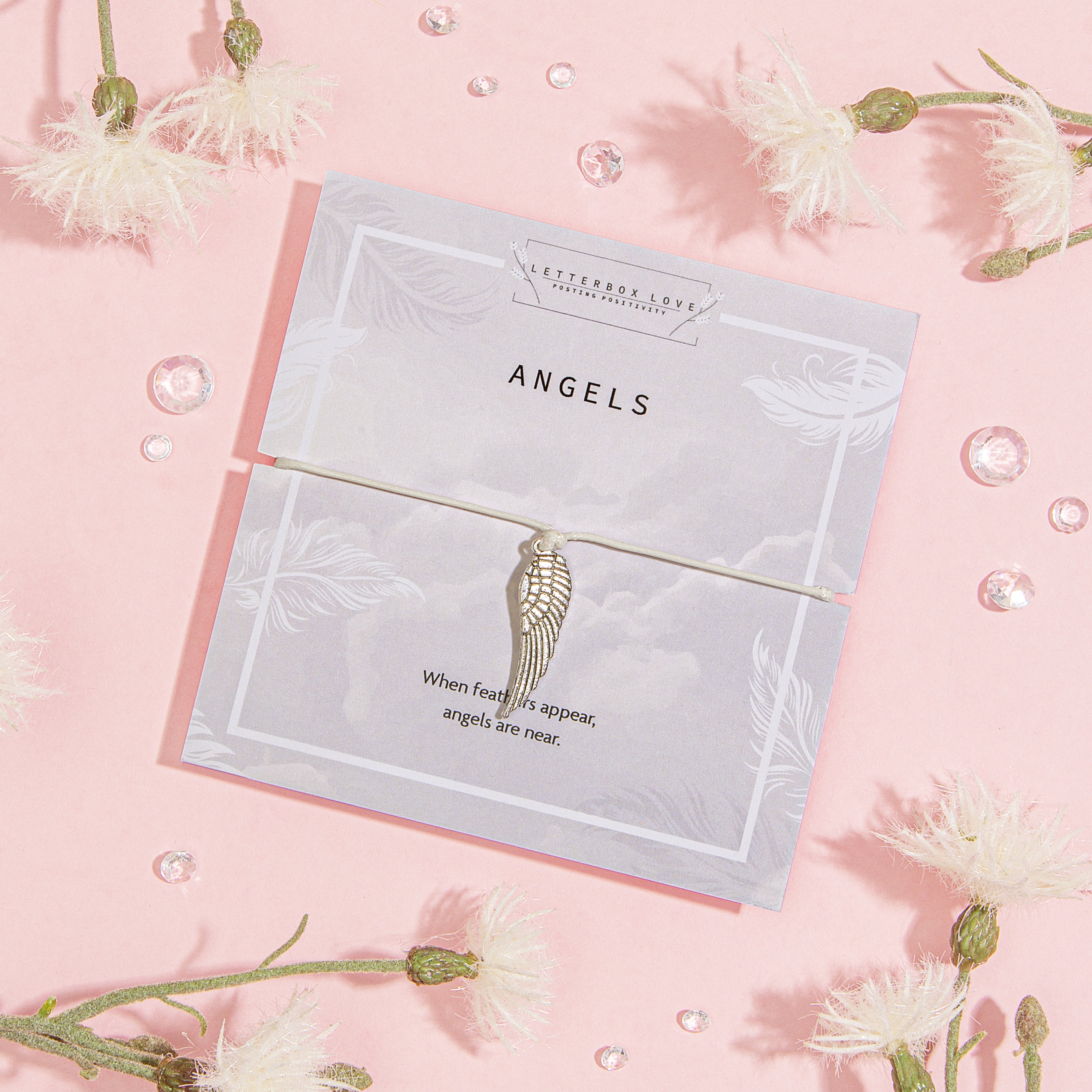 Card with angel wings design on a pink background with flowers