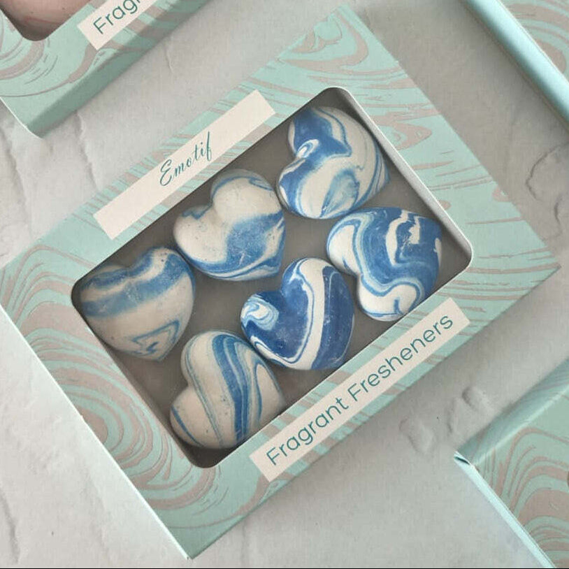 Heart-shaped blue and white marbled fragrant fresheners in a box on a light gray surface.