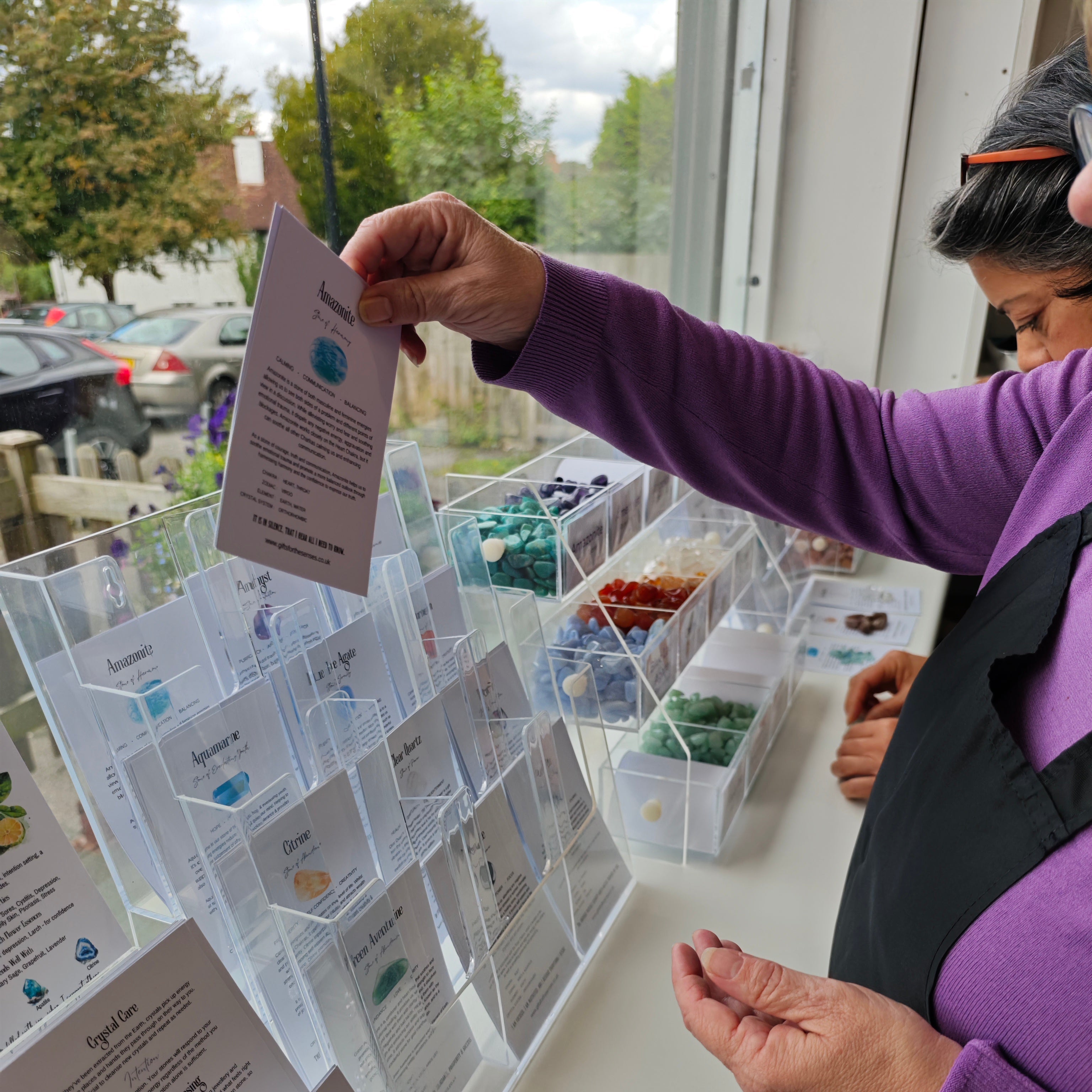 Person looking at a display of small containers with labels and crystals, in a workshop setting.
