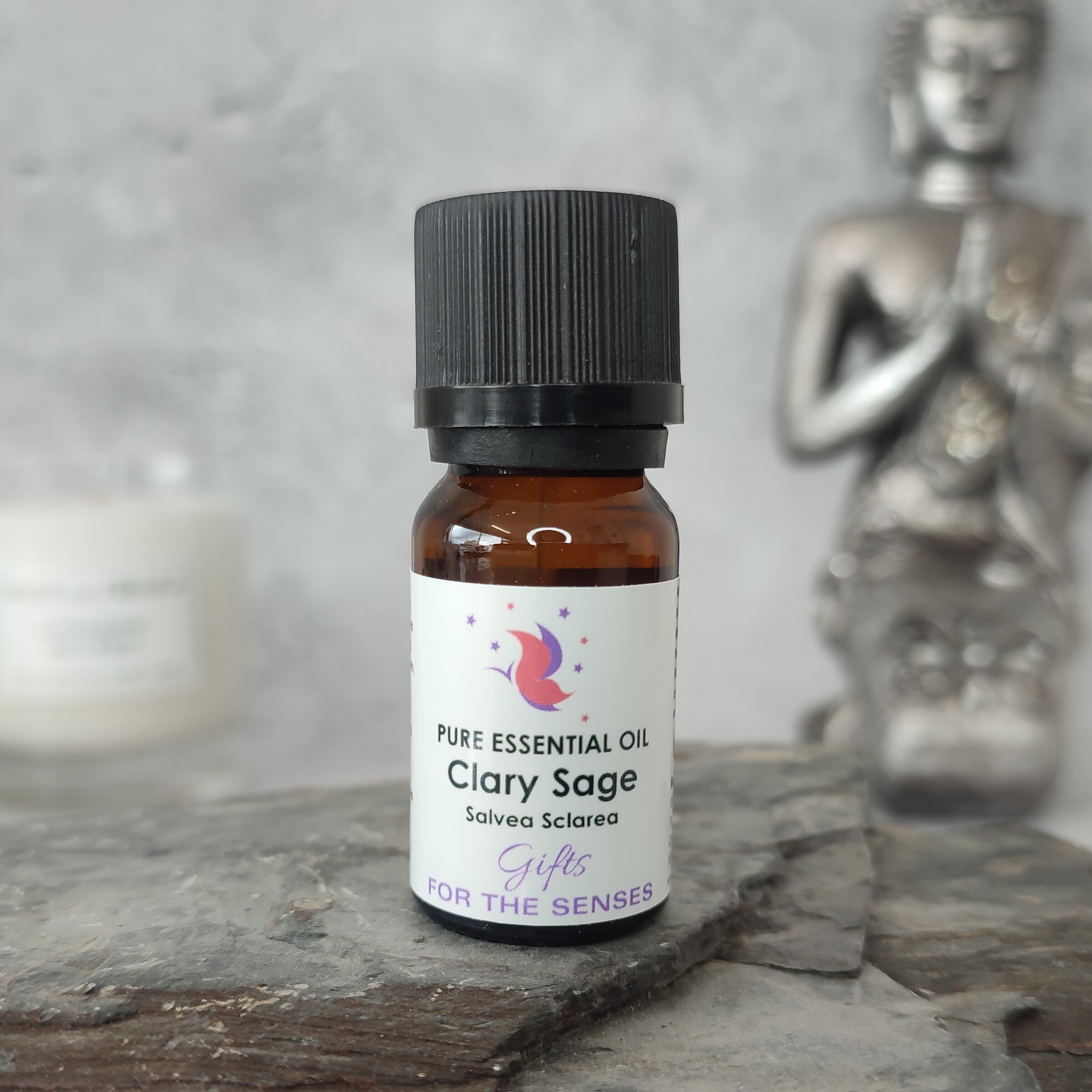 Clary Sage essential oil bottle on a stone surface with a Buddha statue in the background