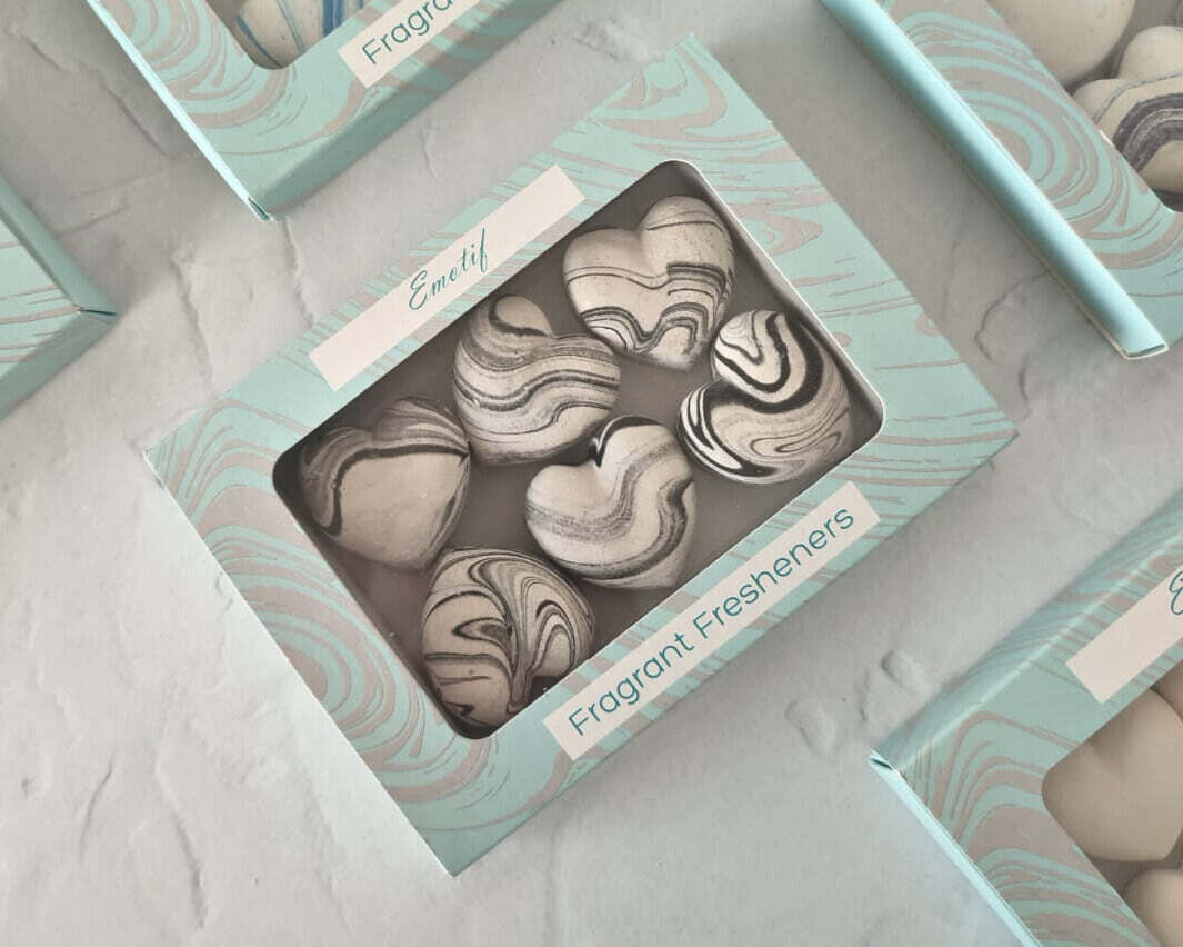 Marble-patterned fragrant fresheners in a decorative box on a light gray surface.
