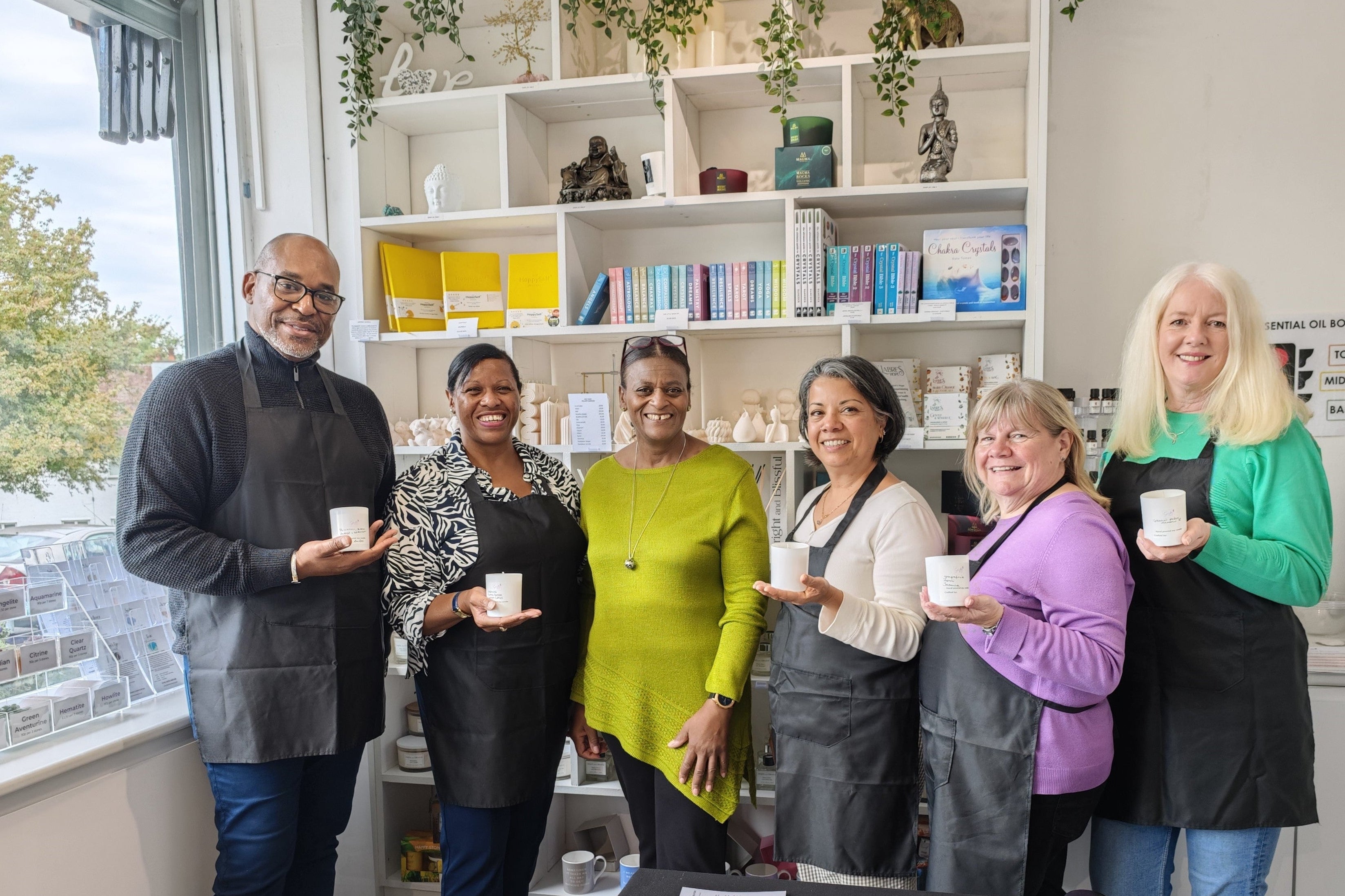 Group of people holding candle containers in a store setting