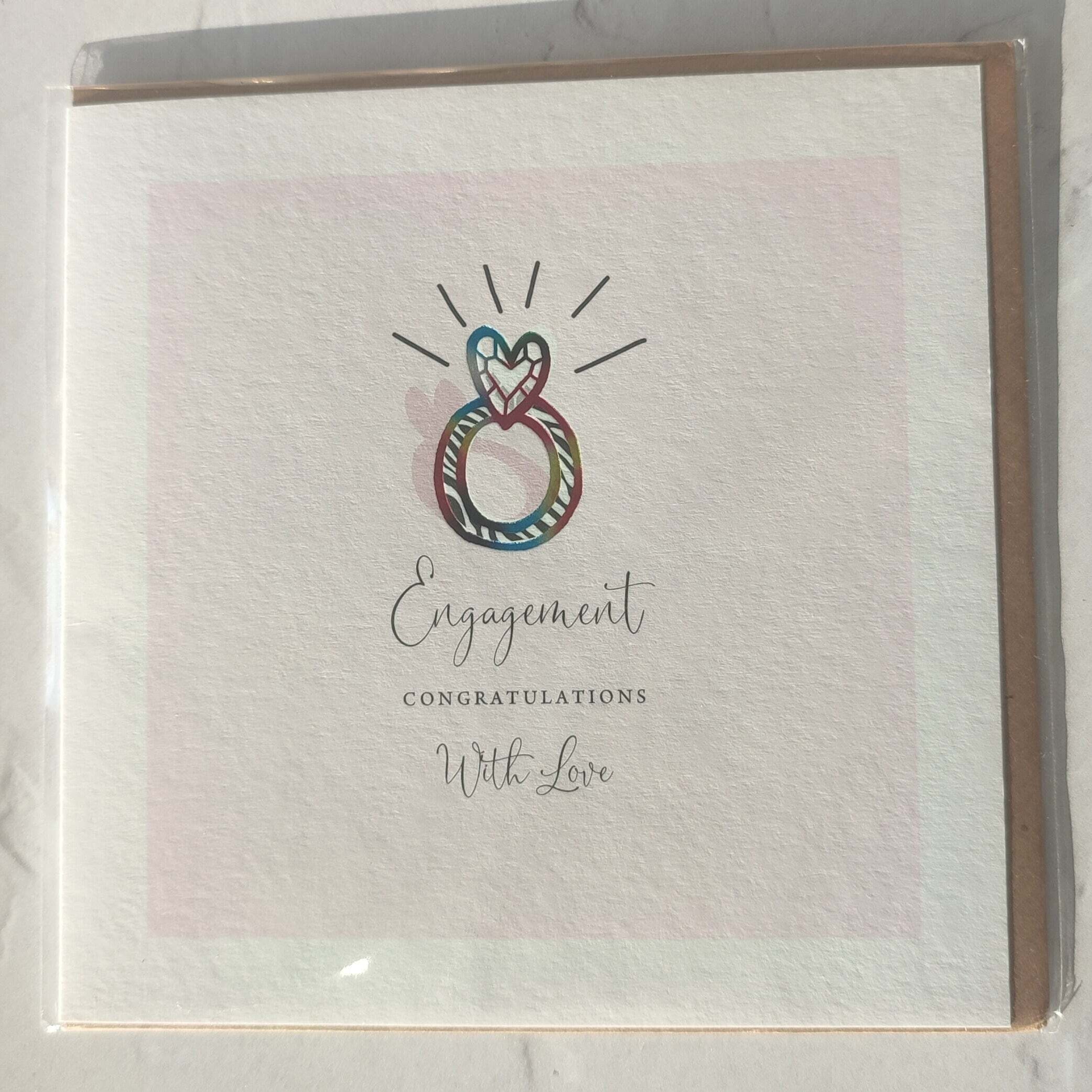 Engagement card with colorful interwoven rings design on a light pink background