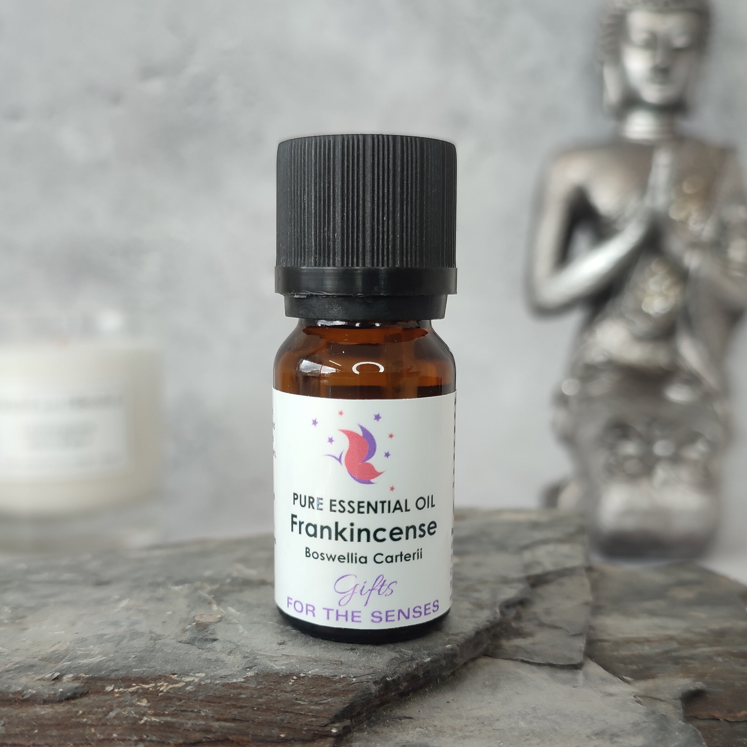 Bottle of Frankincense essential oil on a stone surface with a Buddha statue in the background