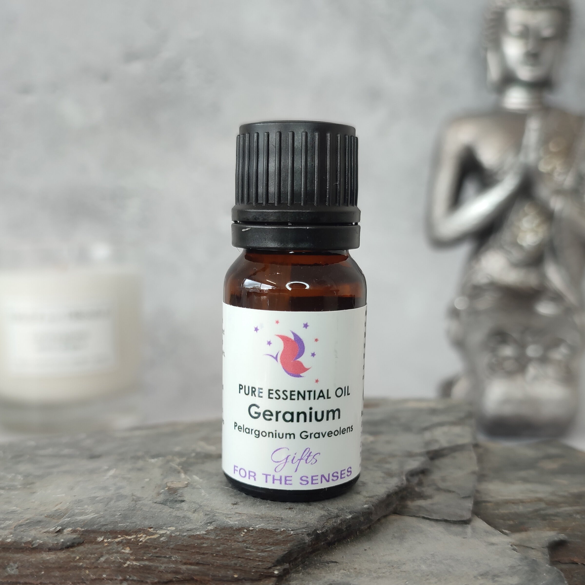 Bottle of Geranium essential oil on a stone surface with a blurred statue in the background