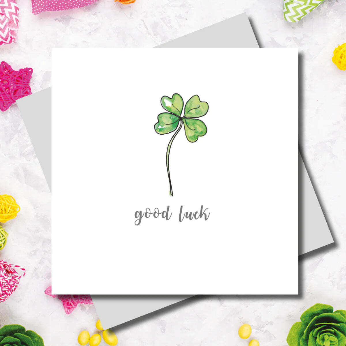 Card with a four-leaf clover illustration and 'good luck' text on a white background with decorative elements.