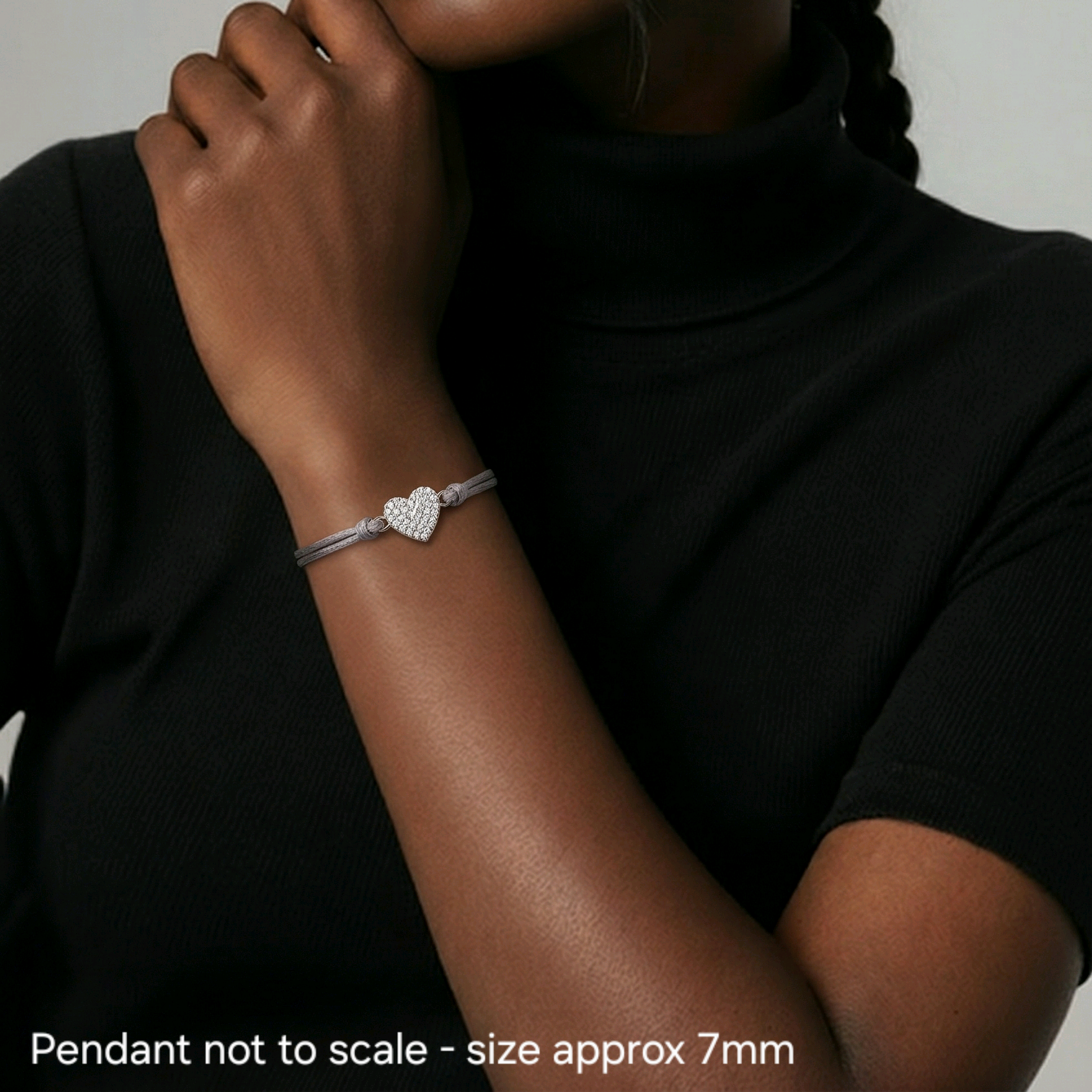 Woman wearing a black turtleneck and bracelet with a star pendant on a neutral background
