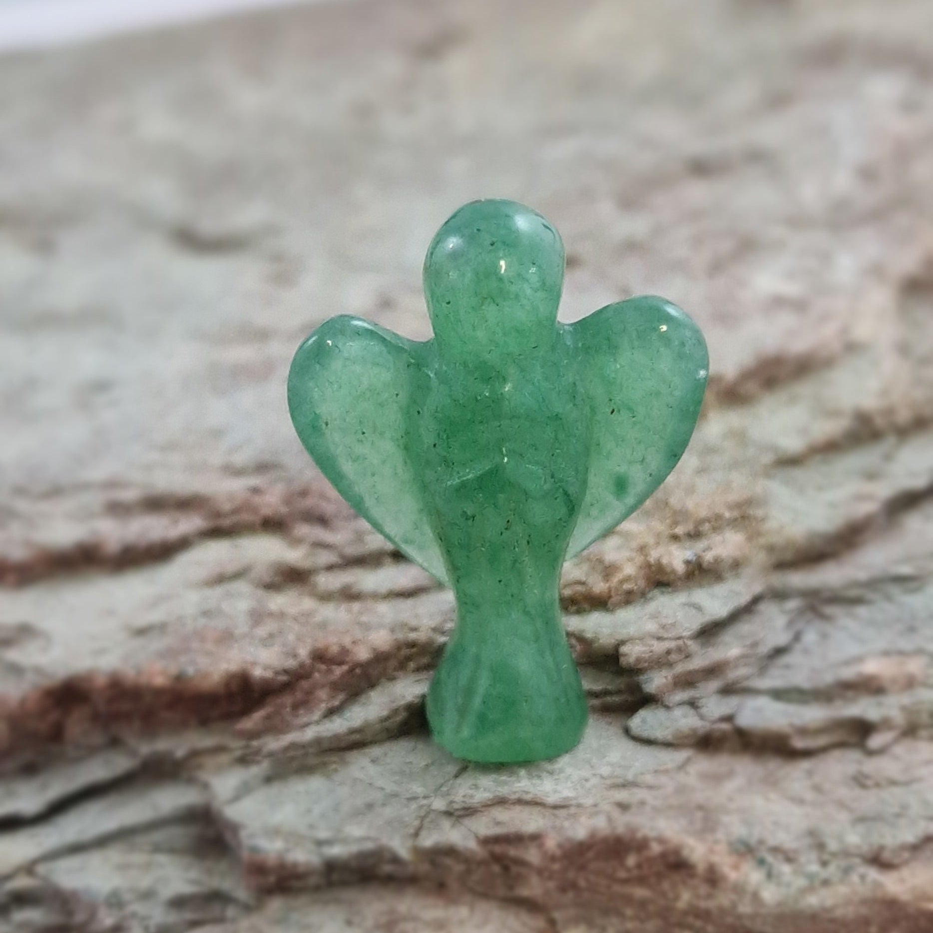 Small Green Aventurine Crystal Angel on a textured surface