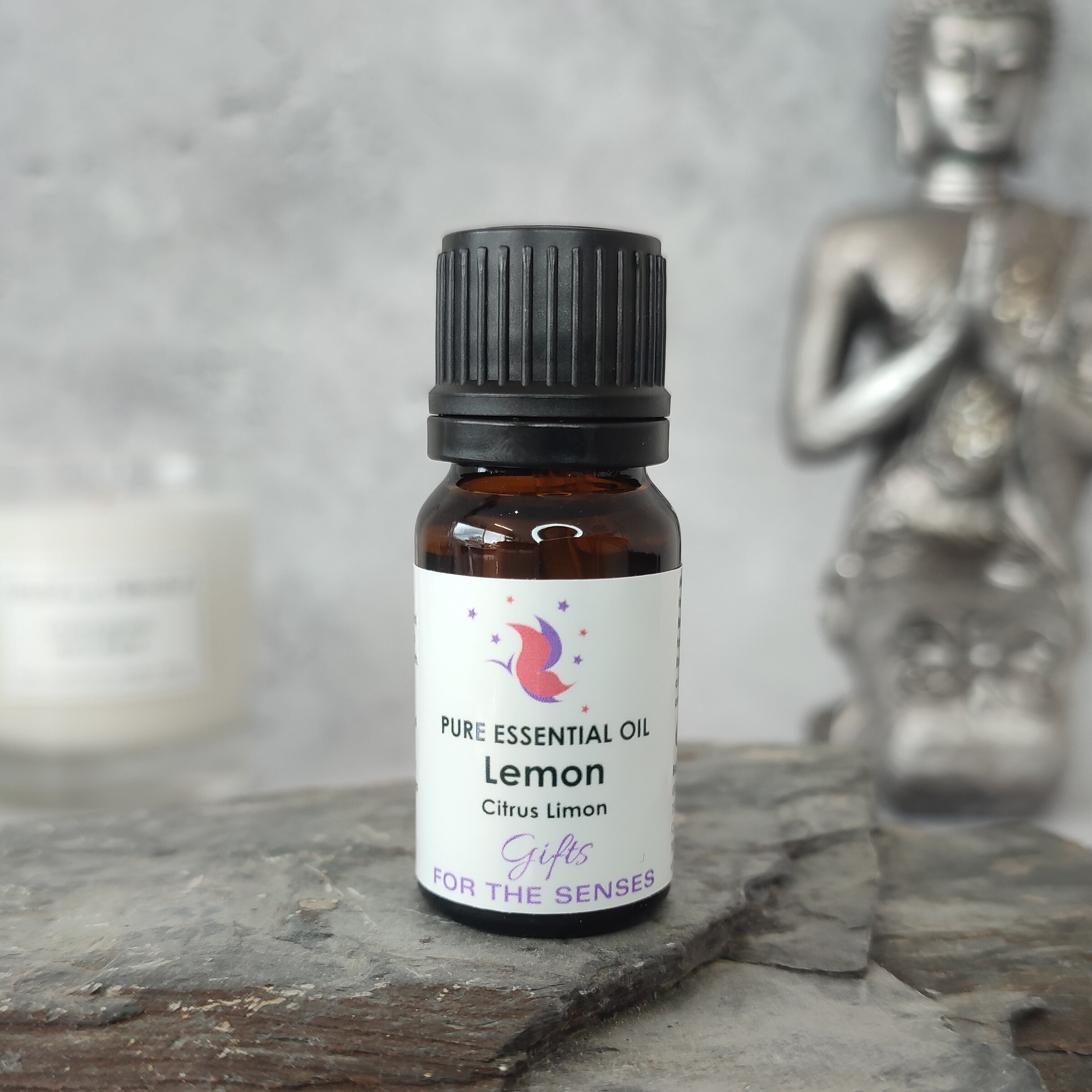 Bottle of lemon essential oil on a stone surface with a Buddha statue in the background