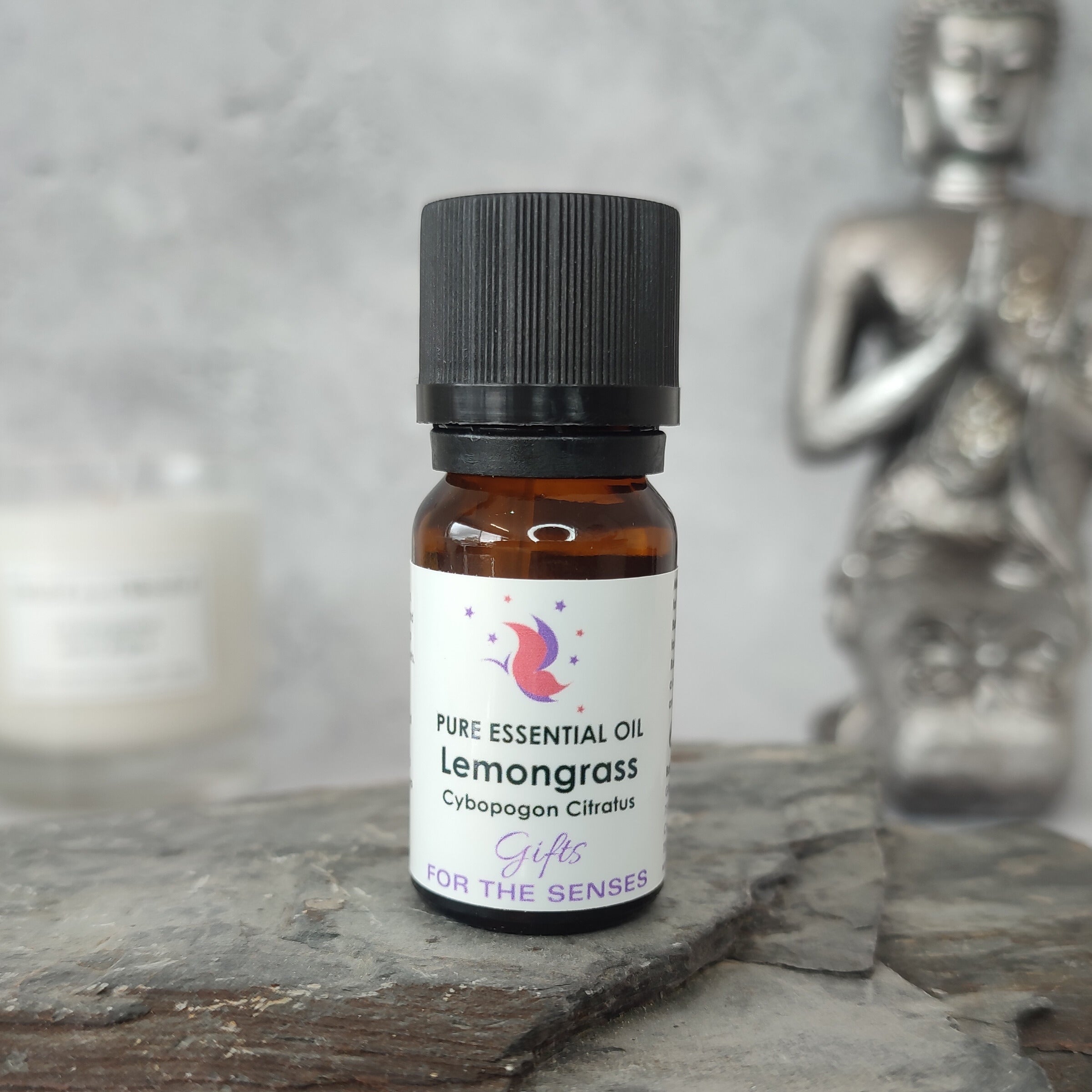 Bottle of lemongrass essential oil on a stone surface with a blurred statue in the background