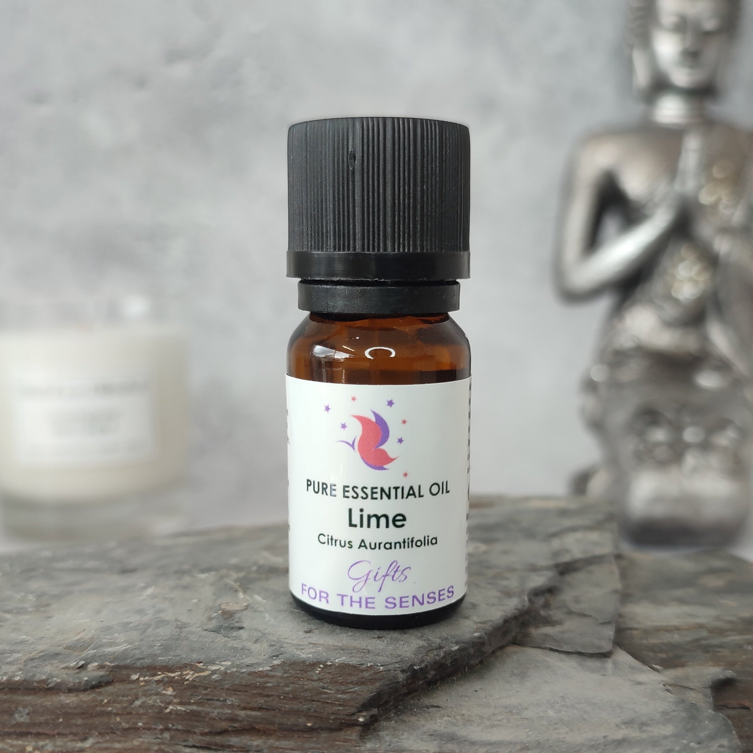 Bottle of pure essential oil labeled 'Lime' on a stone surface with a blurred background
