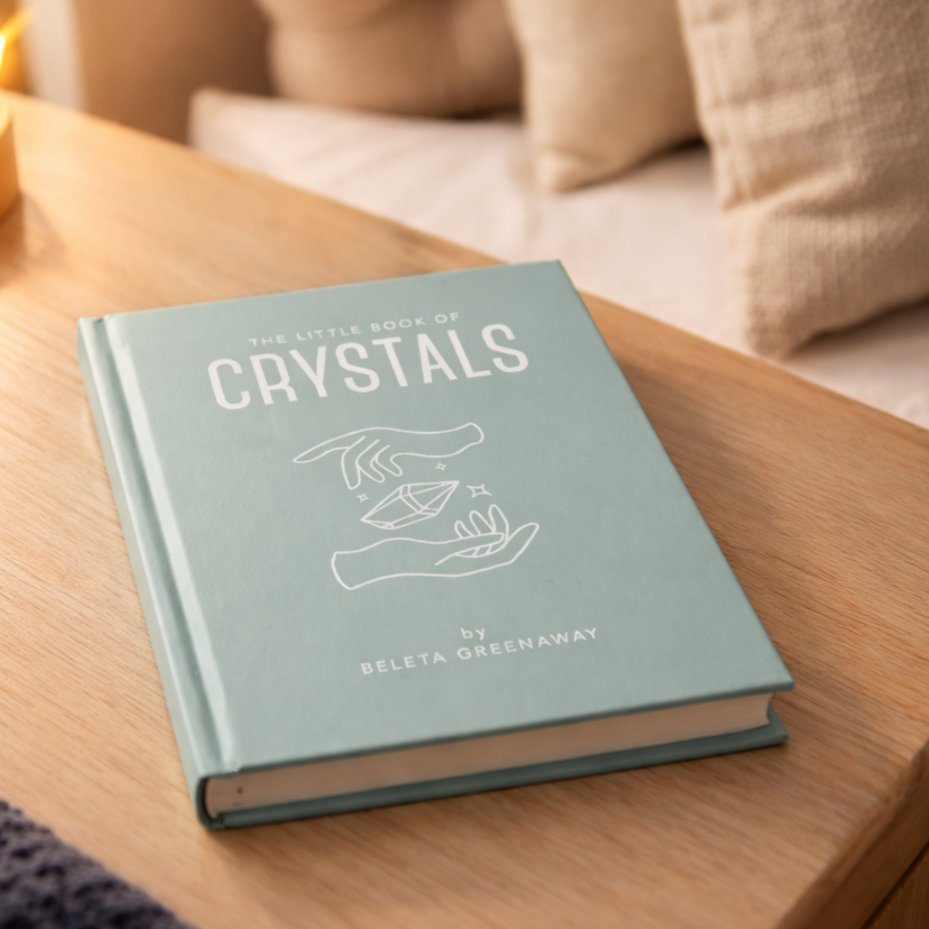The Little Book  of Crystals by Beleta Greenaway on a wooden surface.