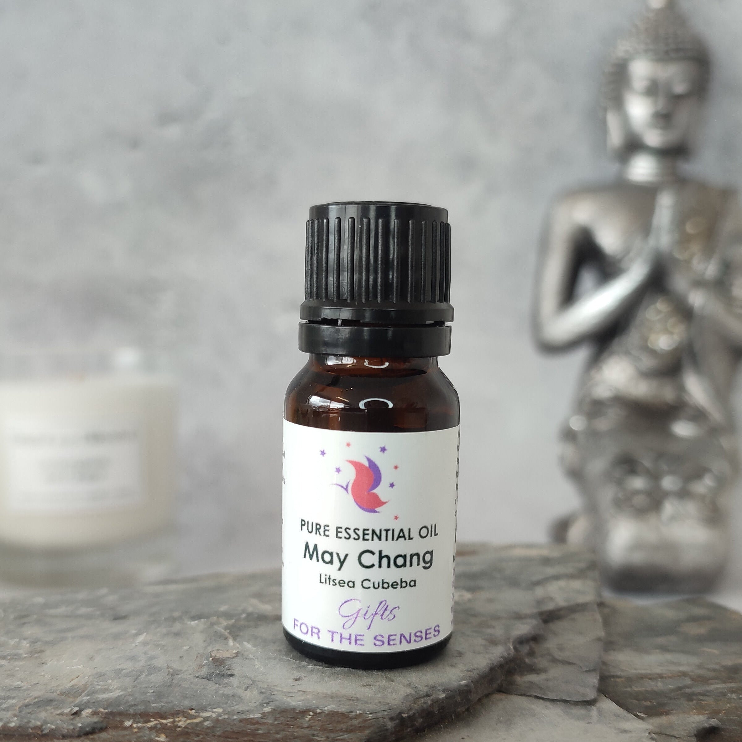 Bottle of May Chang essential oil with a Buddha statue in the background