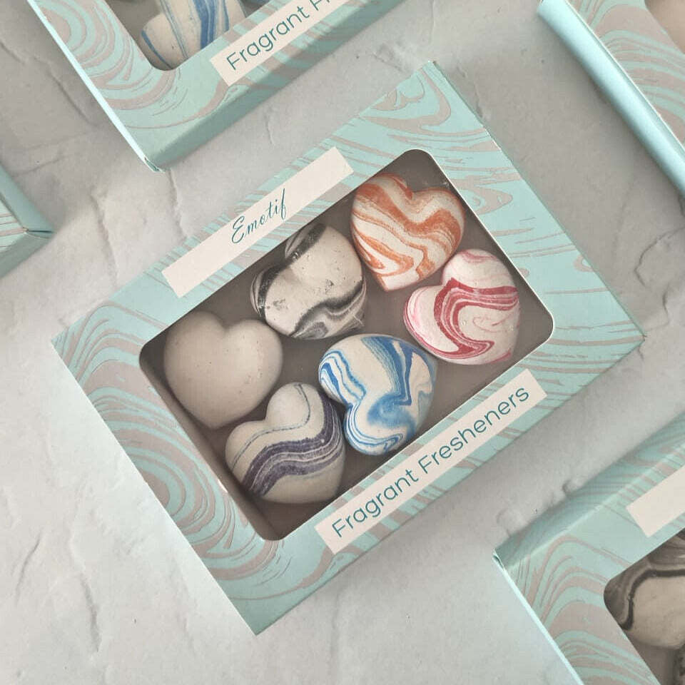 Heart-shaped fragrant fresheners in a box with 'Emotif' branding on a light gray surface.