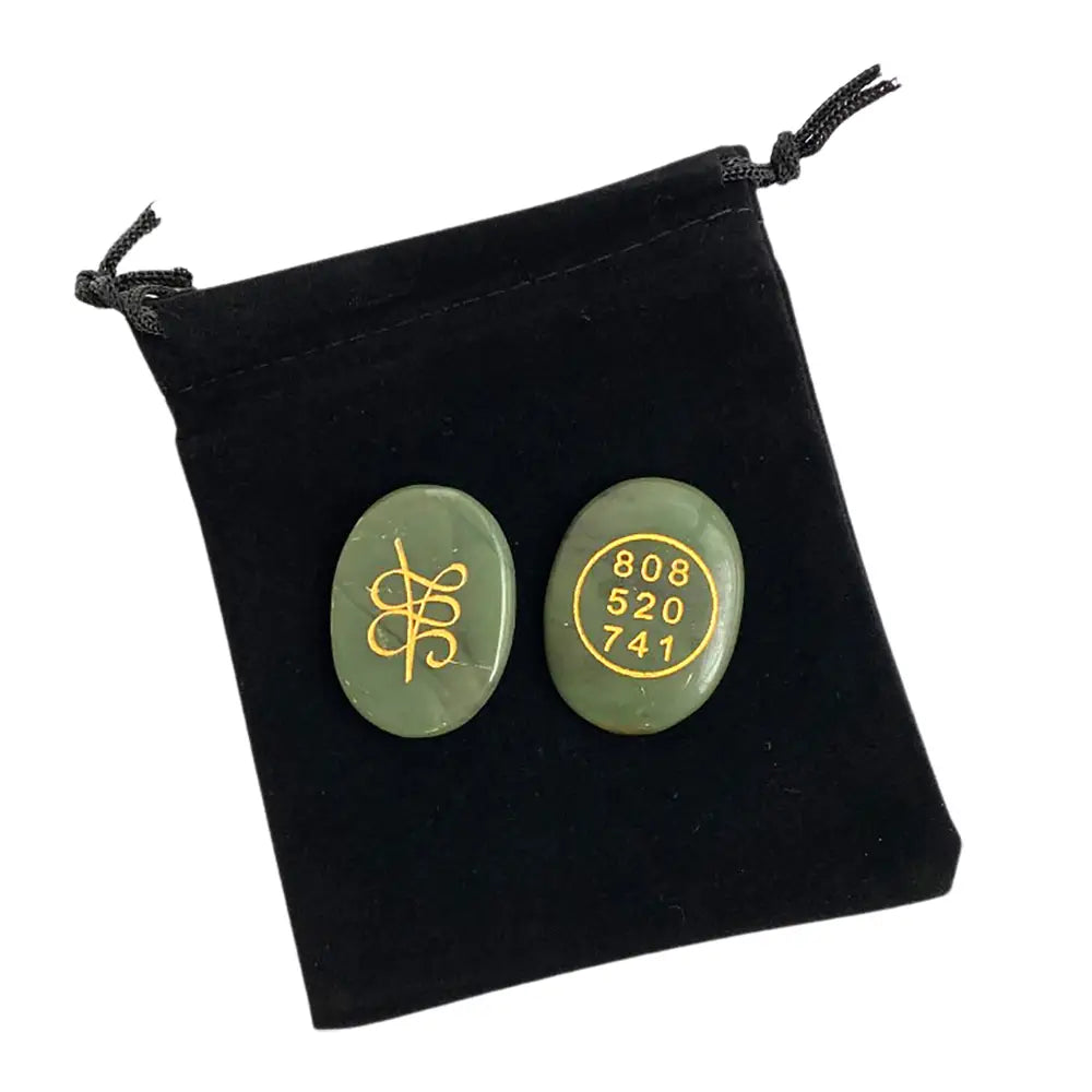 Two green jade stones with gold symbols and numbers on a black drawstring bag