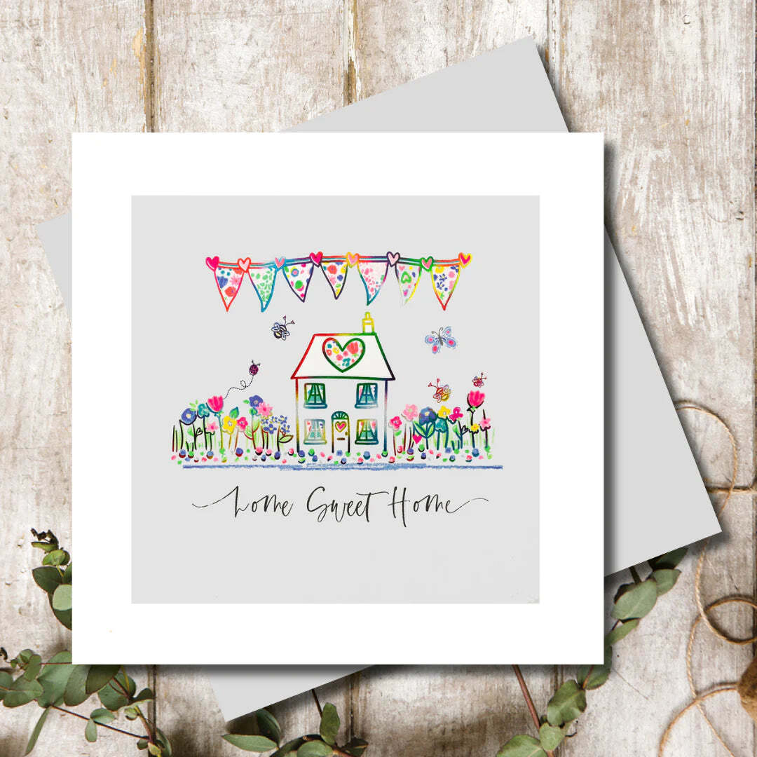 Greeting card with a colorful illustration of a house and bunting on a wooden surface.
