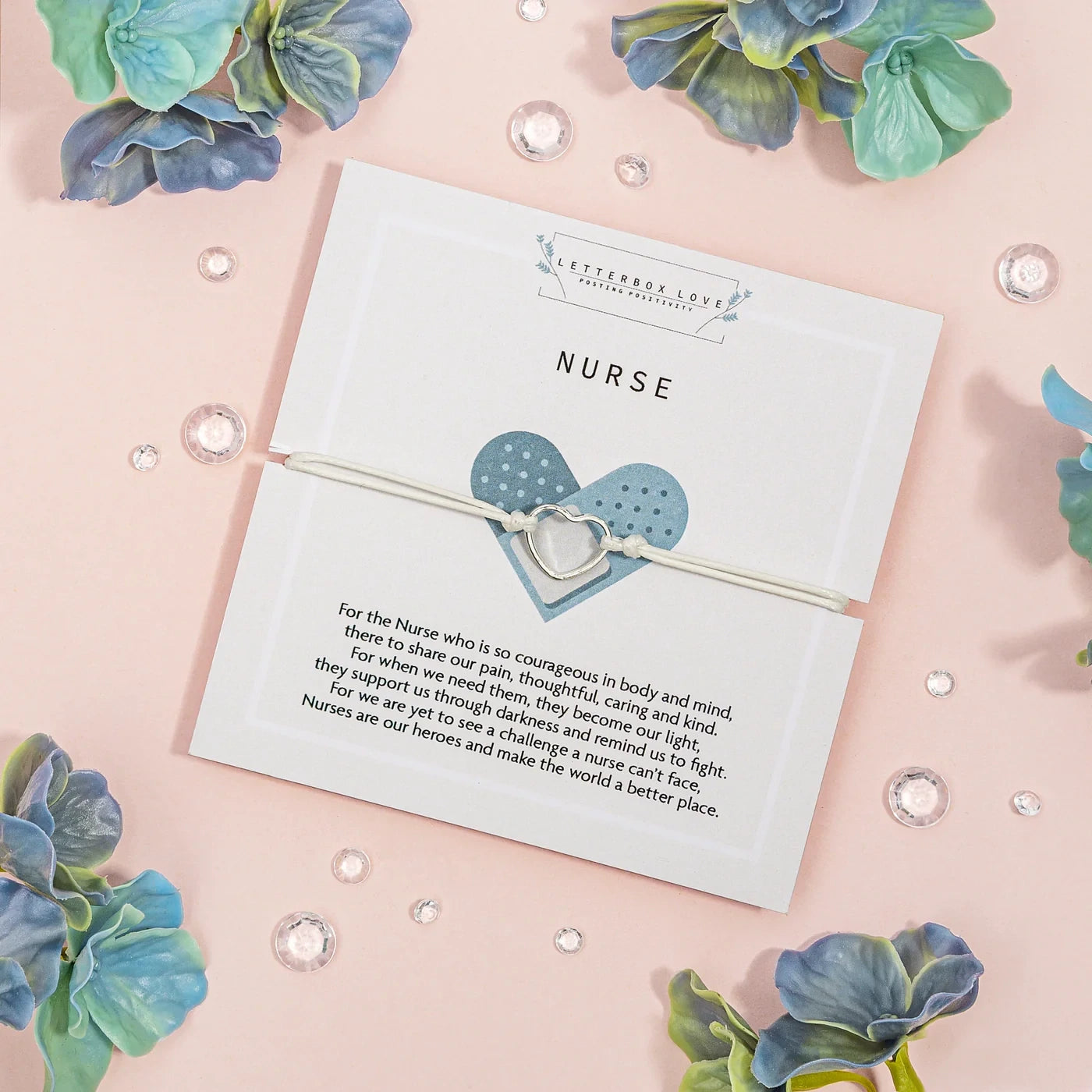 Bracelet with heart design on a card for a nurse, surrounded by decorative flowers on a pink background.