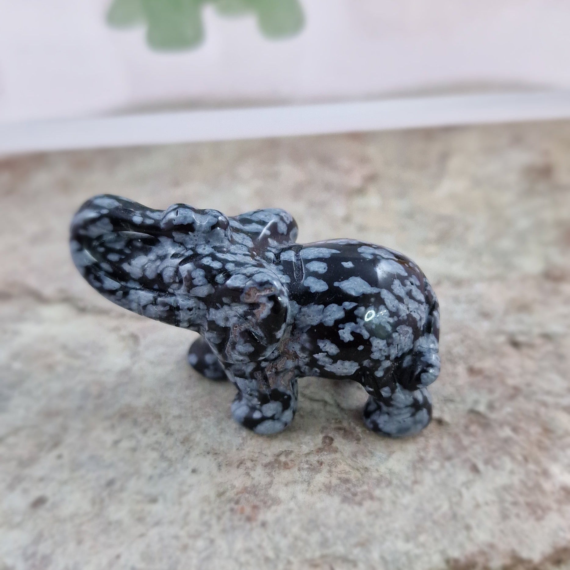 Obsidian Snowflake elephant  on a rock with other crystal elephants in the background