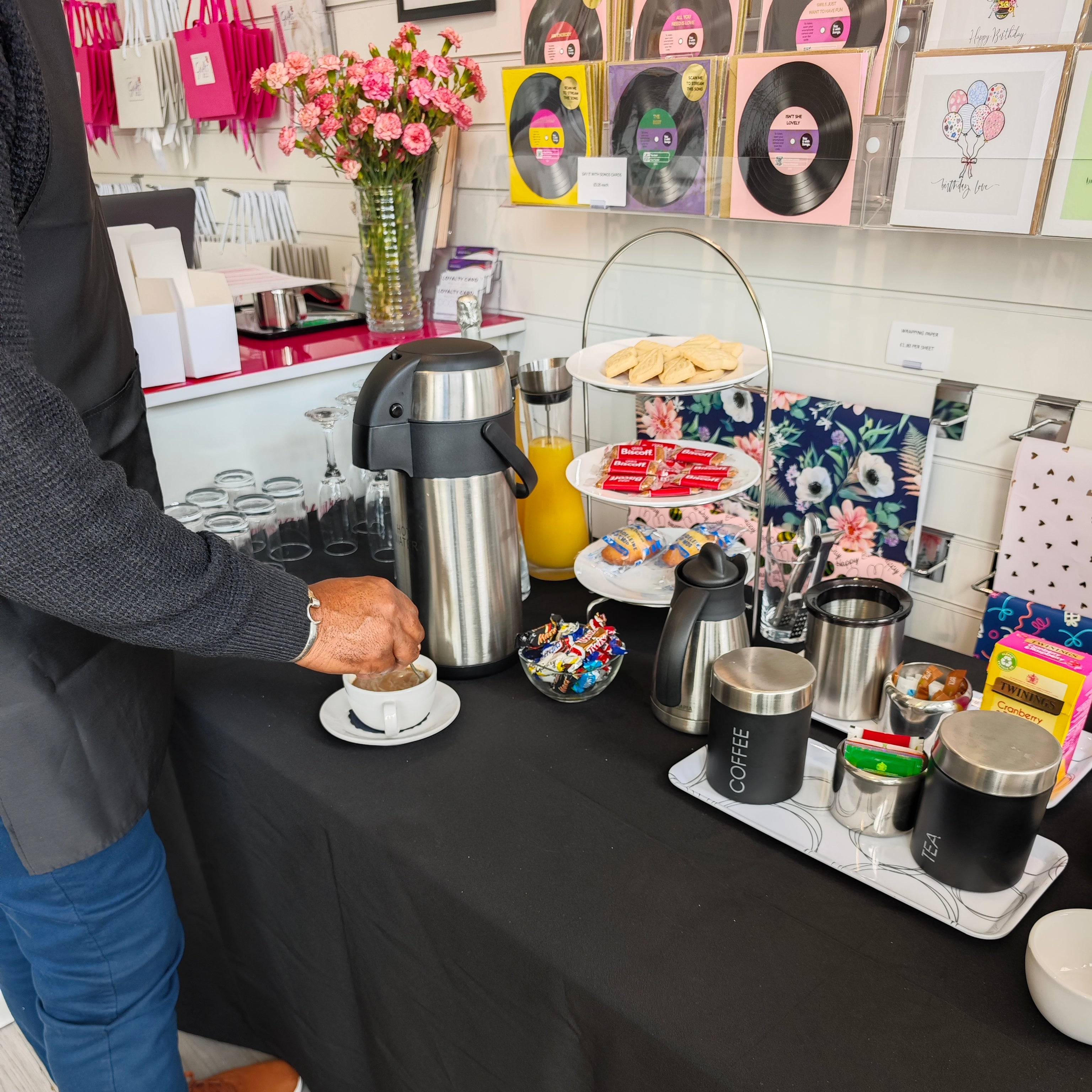 Person at a table with coffee and snacks, surrounded by decorative items.