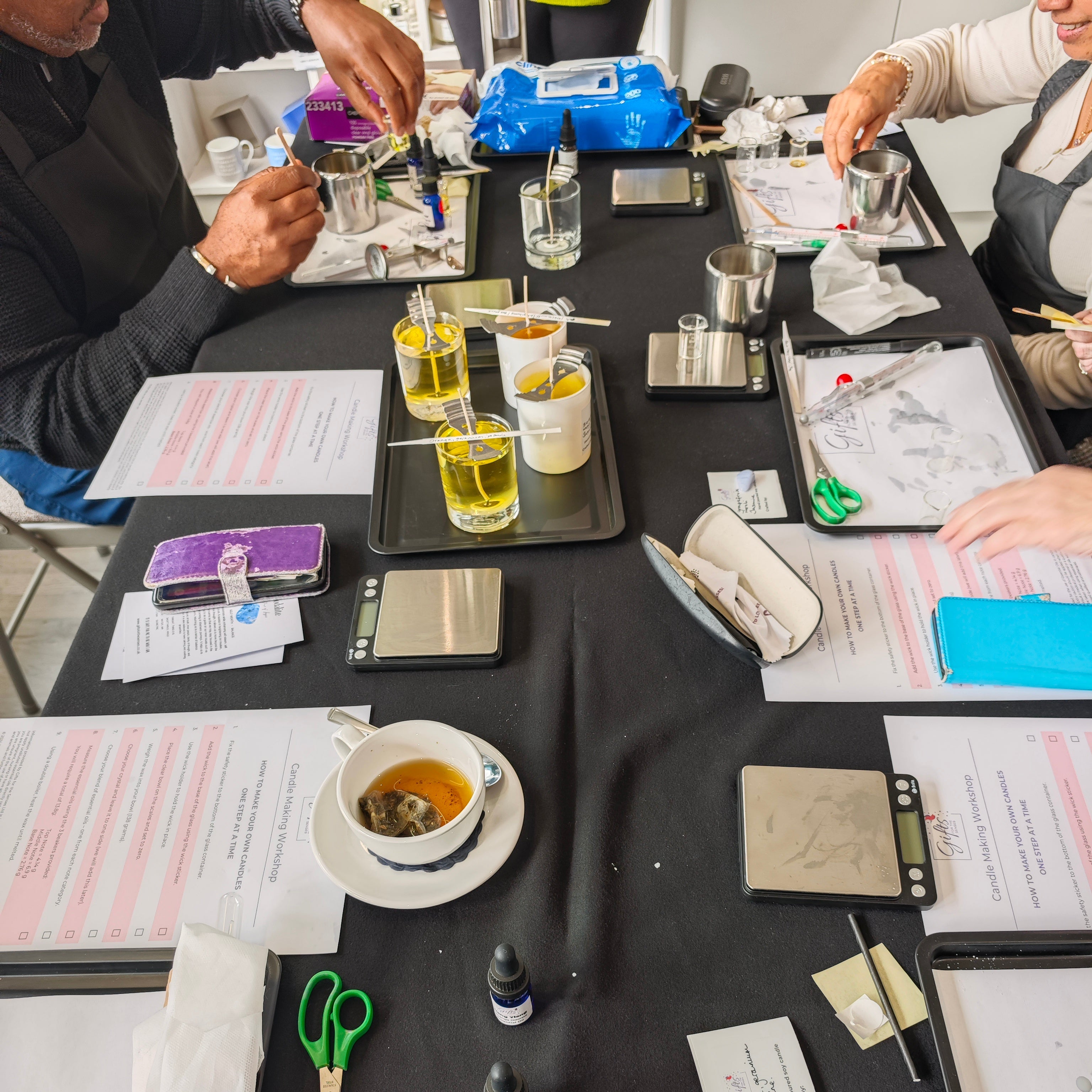 Table with various items including bottles, cups, and papers in a casual setting.