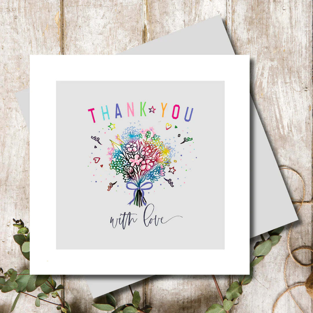 Greeting card with colorful floral design and 'Thank you with love' text on a wooden surface.