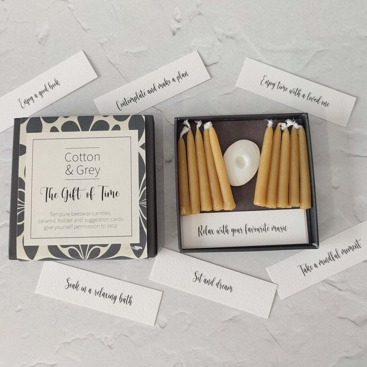 Box of beeswax candles with a card on a textured surface
