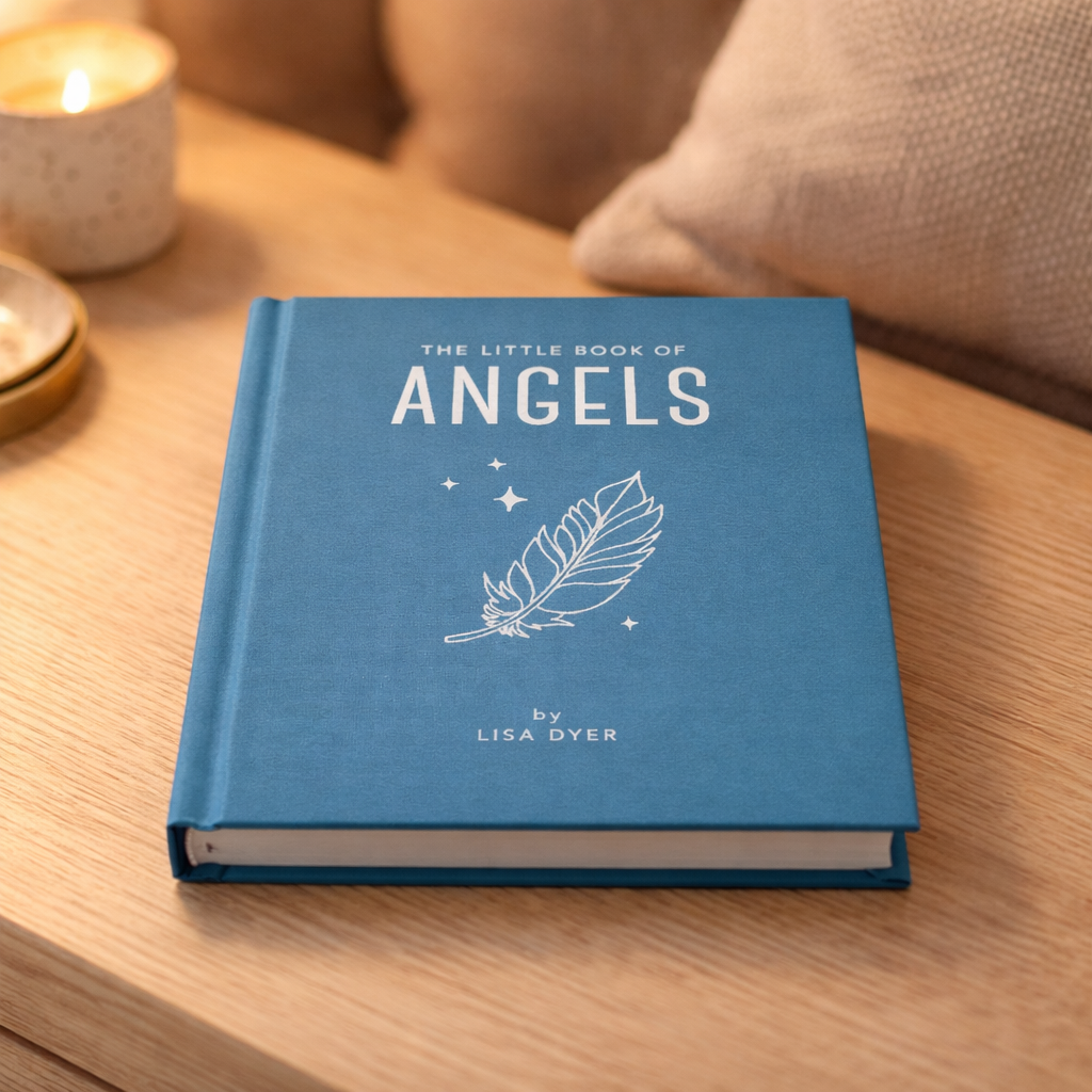 Blue book titled 'The Little Book of Spells' by Lisa Dyer on a wooden table.