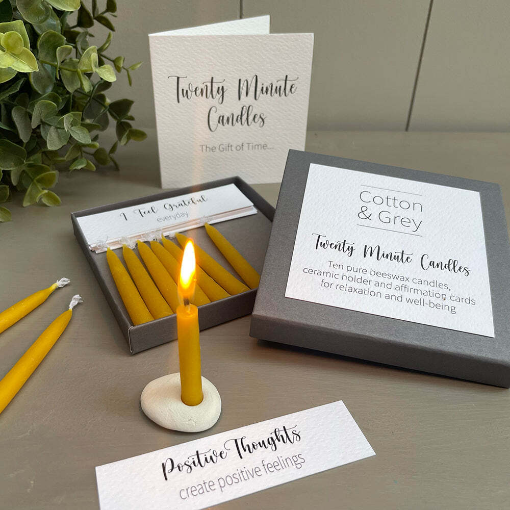 Candle set with 'Twenty Minute Candles' packaging on a table with a plant in the background.